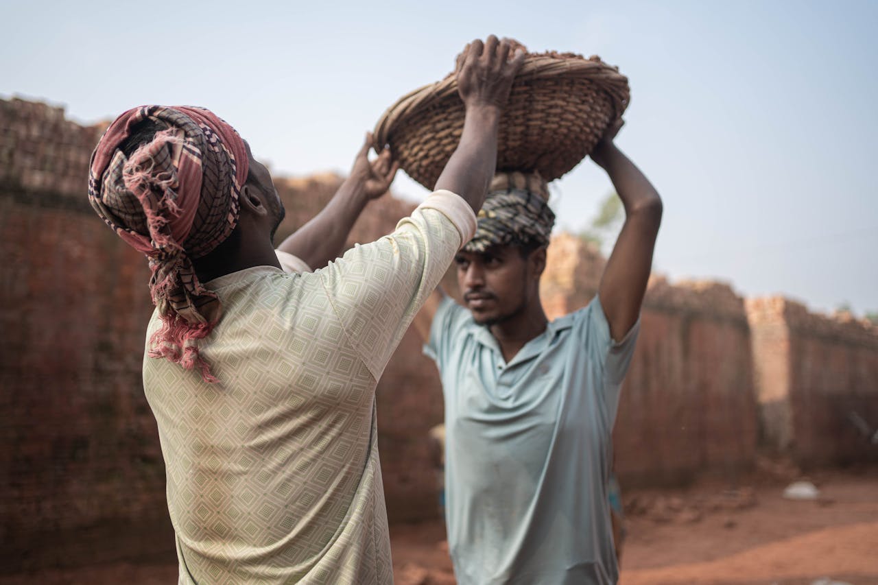 Two male workers in a Dhaka brick field, showcasing hard labor and cooperation.