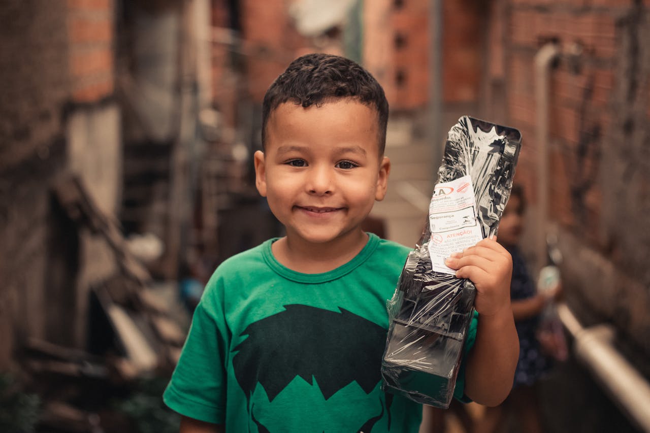 Happy ethnic little kid with new plastic toy car in casual outfit looking at camera