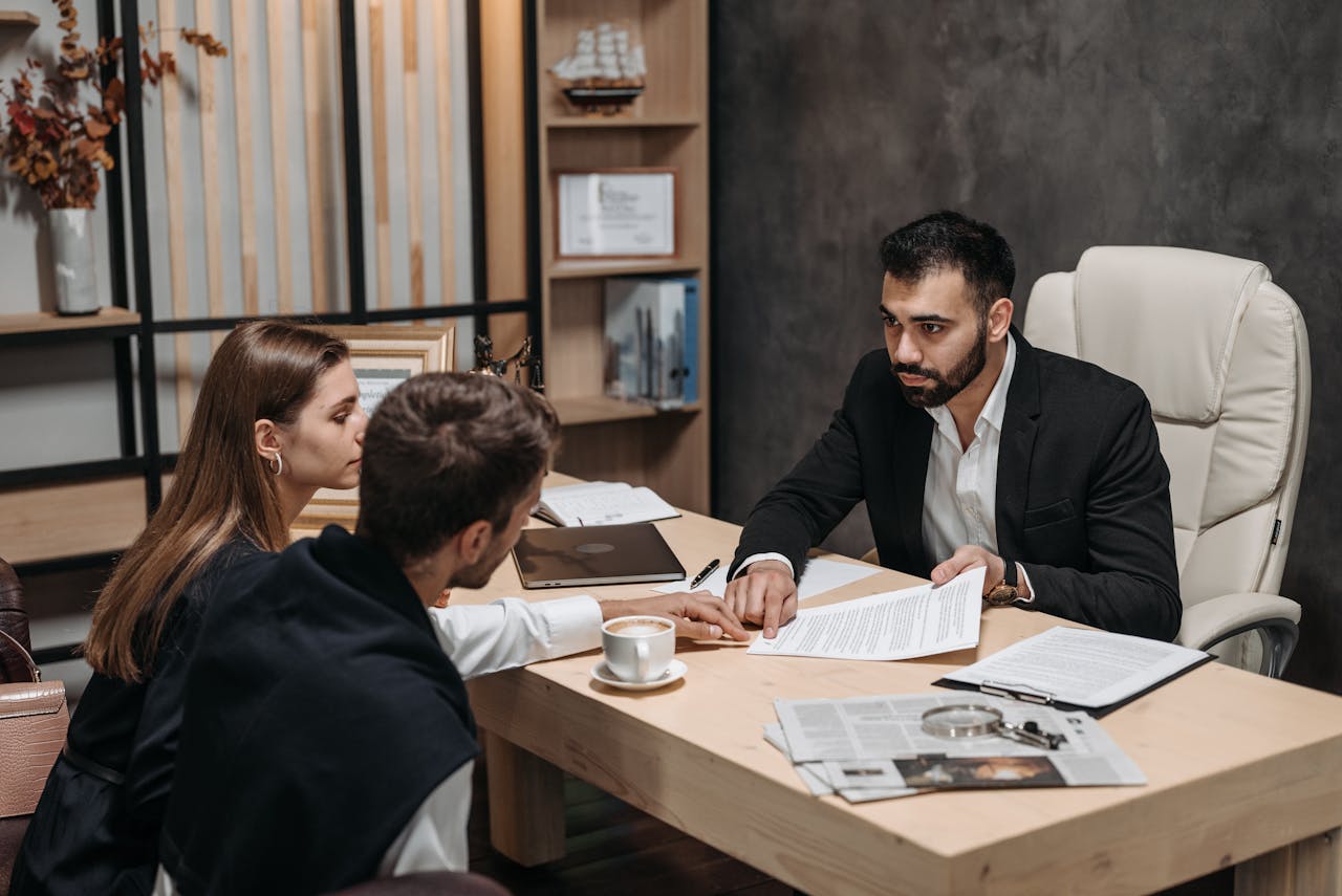 Services-02 Lawyer discussing legal documents with clients at office desk.